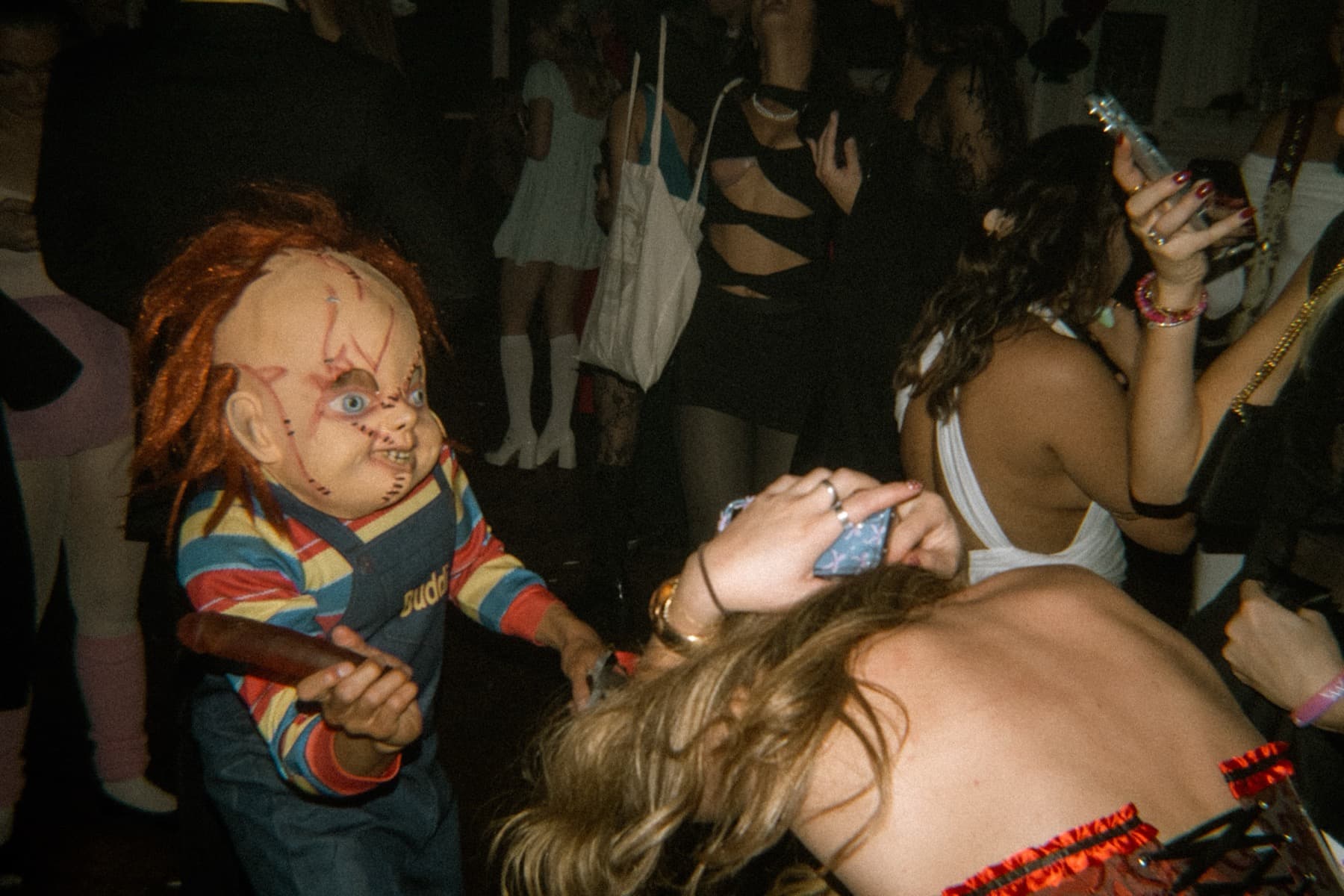 Person in a Chucky doll costume dancing on the crowded party floor