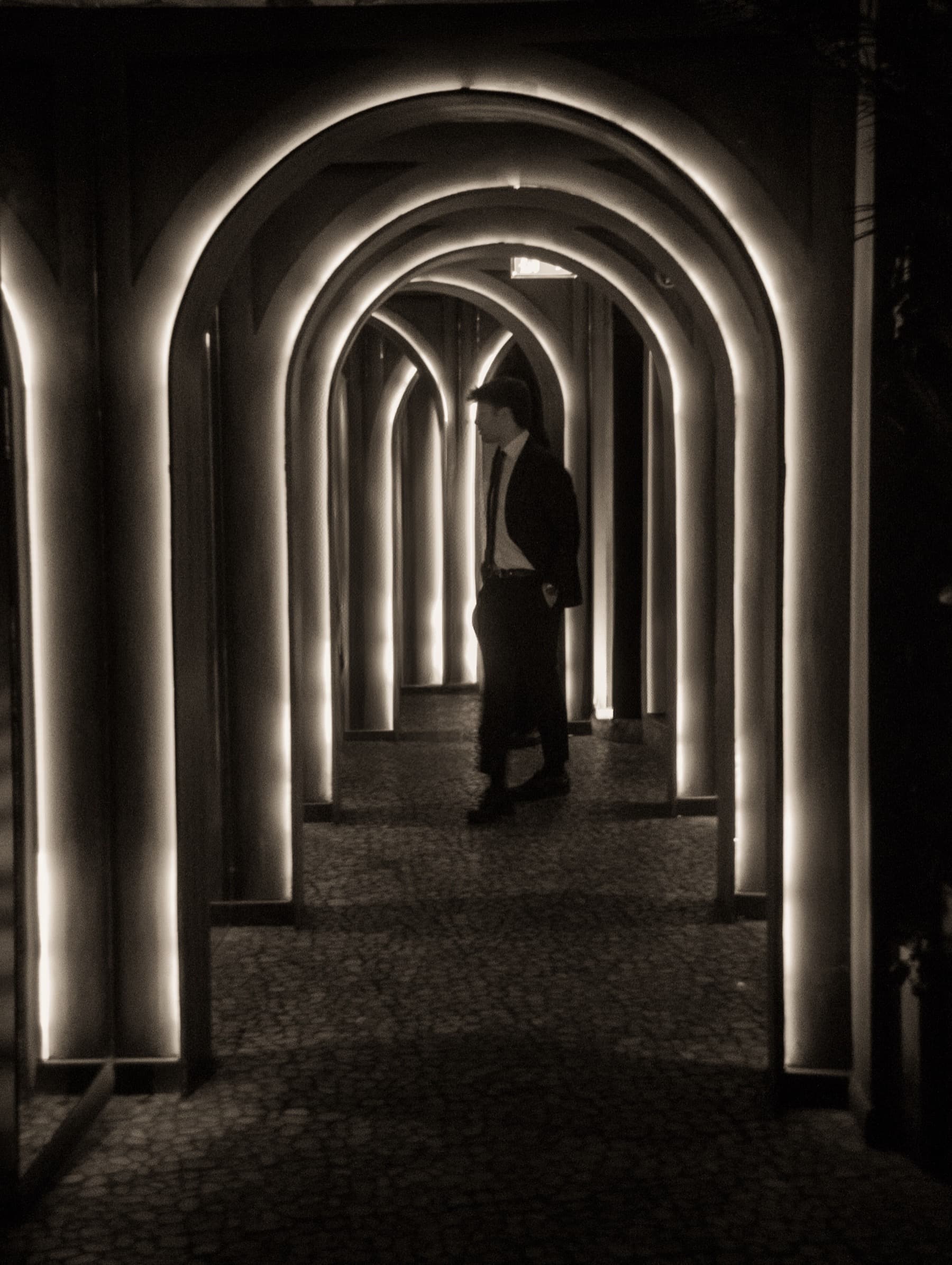 Silhouette of a figure walking through a tunnel of illuminated arches at the club entrance