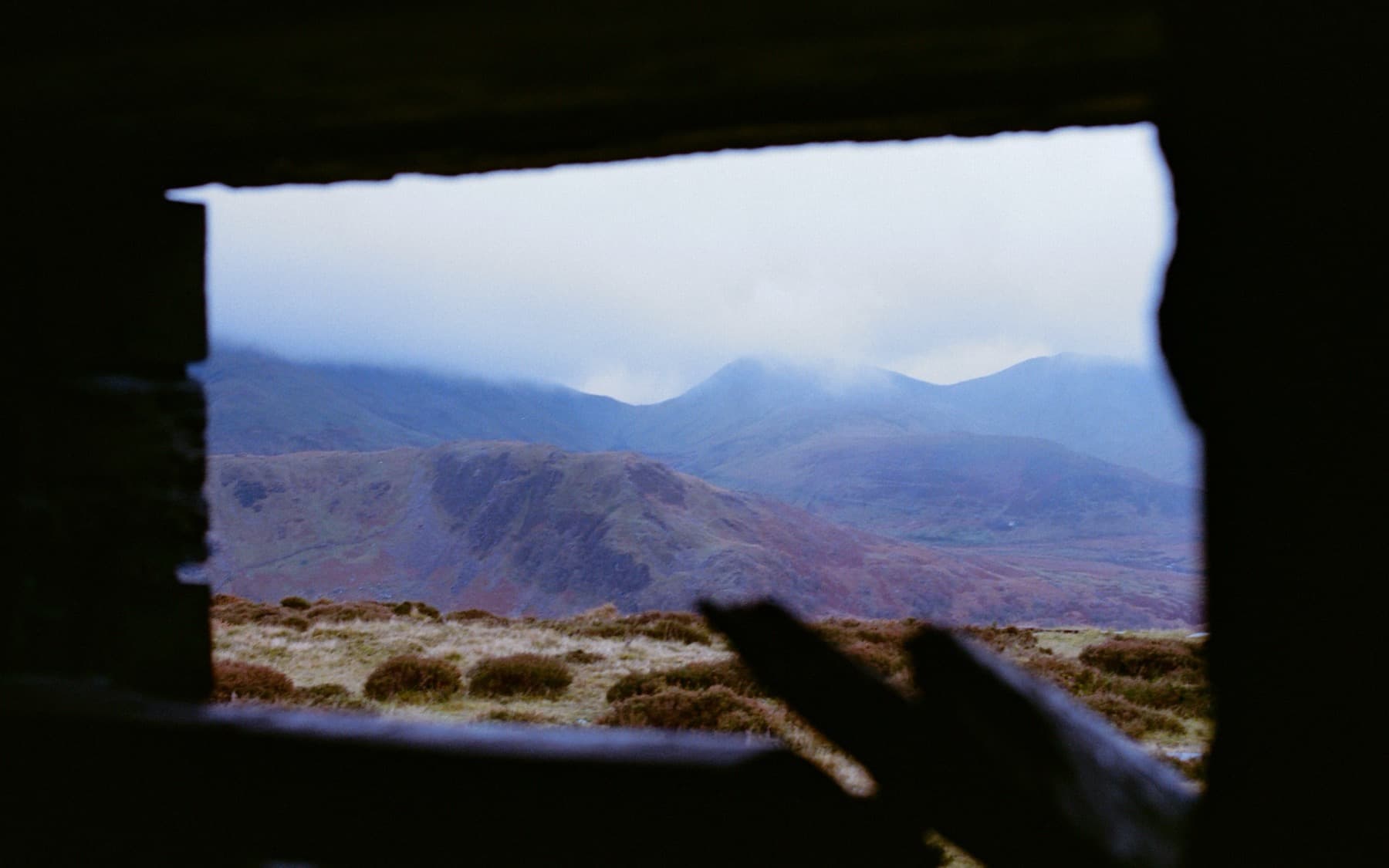 Misty mountain panorama viewed through the window of a ruined quarry building, shot on film