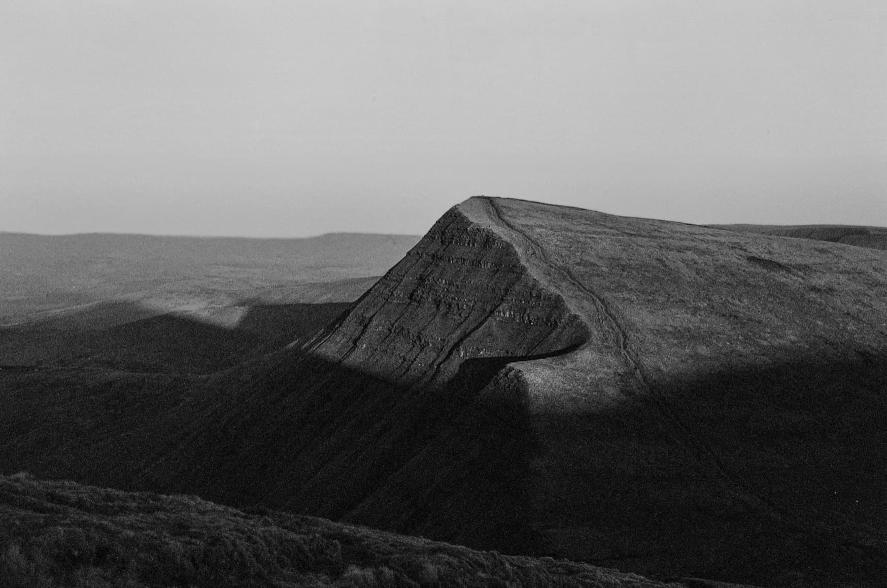 The pointed ridge of Cribyn casting deep shadows across the hillside in black and white film