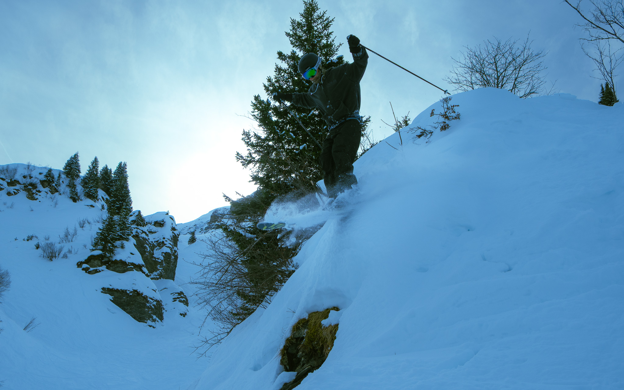 Skier dropping off a rocky cliff edge into powder snow